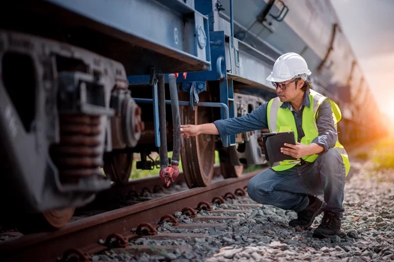 Mitarbeiter der Eisenbahn überprüft den Zustand eines Schienenfahrzeugs