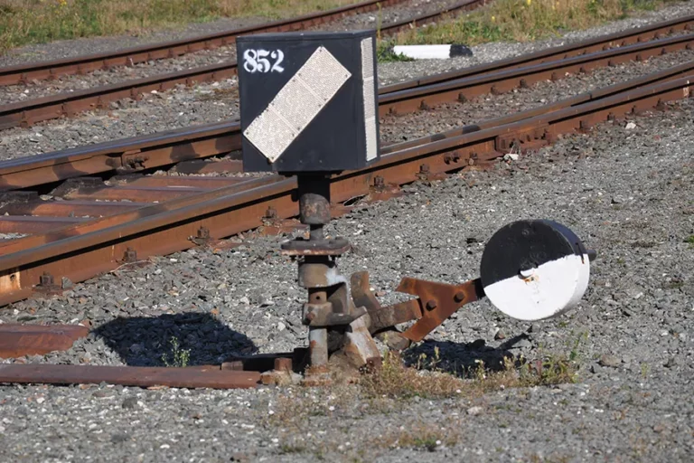 Nahaufnahme Eisenbahn-Weichensteller auf Schotter mit Schienen im Hintergrund