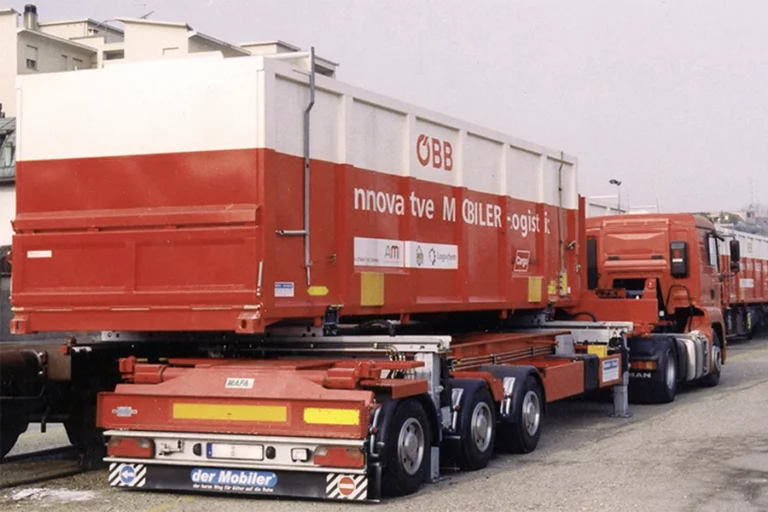 Wechselbehälter wird seitlich von LKW auf Güterwaggon geladen